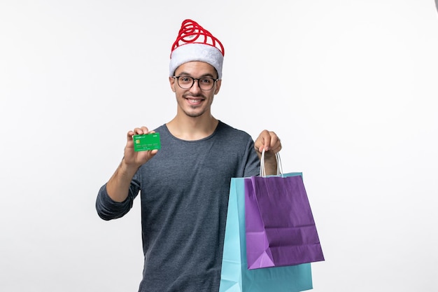 Vista frontal del joven con regalos y tarjeta bancaria en la pared blanca