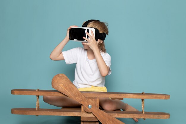 Vista frontal joven rubio pelo adorable dulce lindo jugando vr gafas sobre fondo azul.