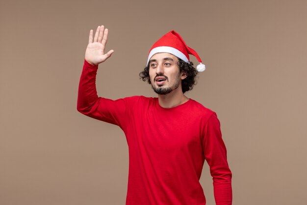 Vista frontal joven saludando sobre el fondo marrón Navidad emoción vacaciones