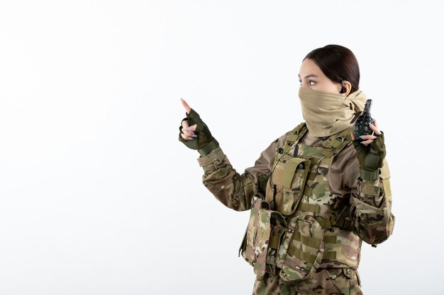 Vista frontal del joven soldado en camuflaje con pared blanca de granada