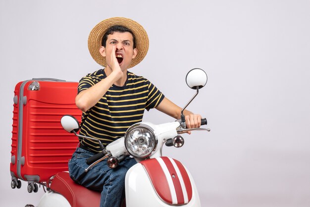 Vista frontal del joven con sombrero de paja en ciclomotor gritando