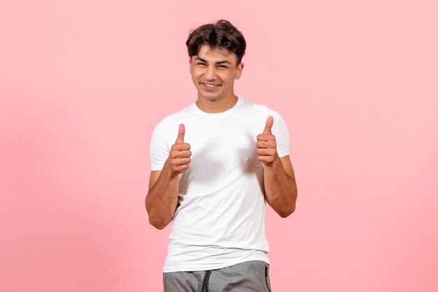 Vista frontal joven sonriente en camiseta blanca sobre fondo rosa