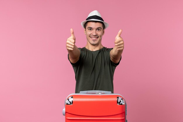 Vista frontal joven sonriente en vacaciones con bolsa grande en espacio rosa