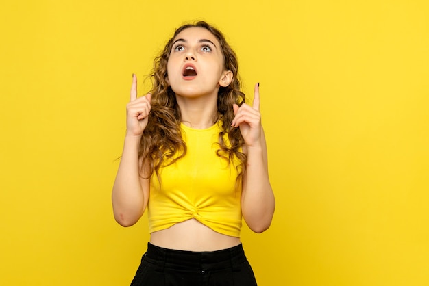 Vista frontal de la joven sorprendida en la pared amarilla