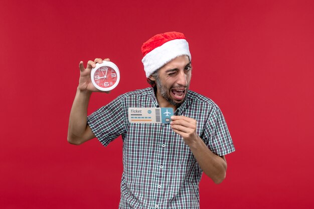 Vista frontal joven sosteniendo el billete y el reloj en la pared roja roja emoción tiempo masculino