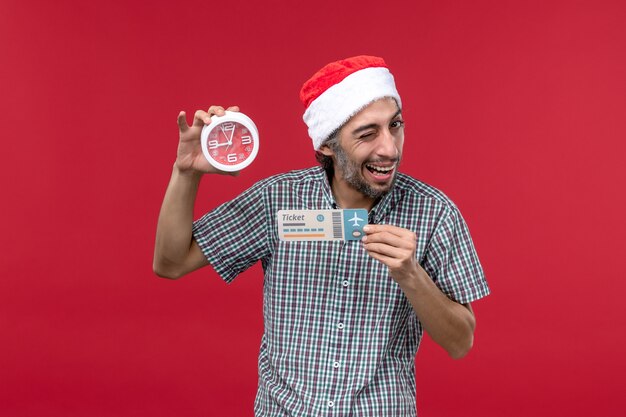 Vista frontal joven sosteniendo el billete y el reloj en la pared roja roja emoción tiempo masculino