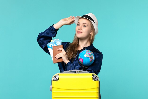 Vista frontal joven sosteniendo la billetera con boletos en el fondo azul viaje en avión mujer viaje mar vacaciones