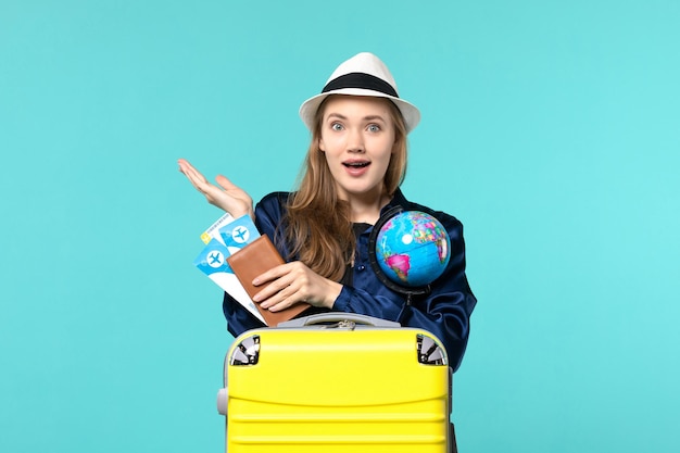 Vista frontal joven sosteniendo boletos y globo sobre el fondo azul viaje en avión viaje de vacaciones por mar