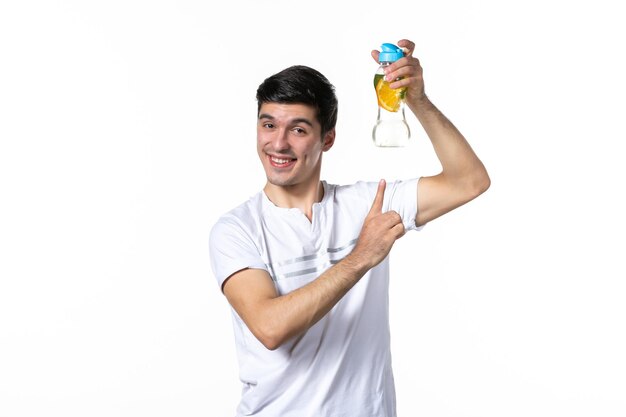 Vista frontal joven sosteniendo una botella de limonada en la superficie blanca