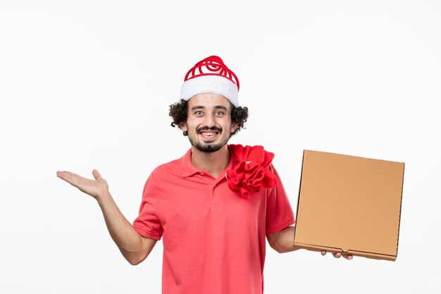 Vista frontal del joven sosteniendo la caja de comida de entrega en la pared blanca