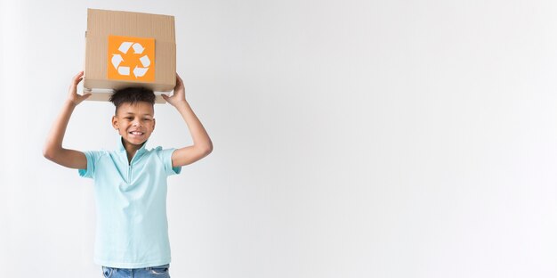 Vista frontal joven sosteniendo la caja de reciclaje con espacio de copia