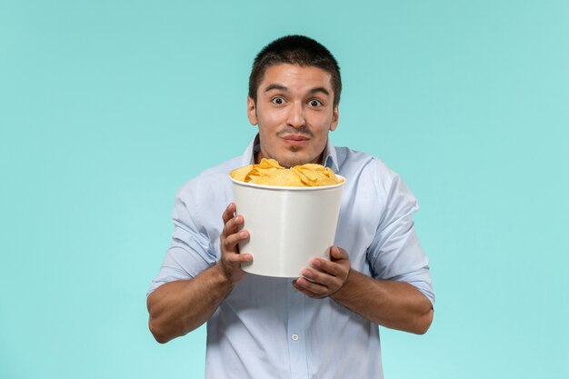 Vista frontal joven sosteniendo la canasta con cips en la película de escritorio azul películas remotas cine cine