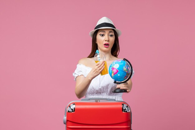 Vista frontal joven sosteniendo globo y cóctel en el piso rosa viaje viaje de verano vacaciones de color de calor