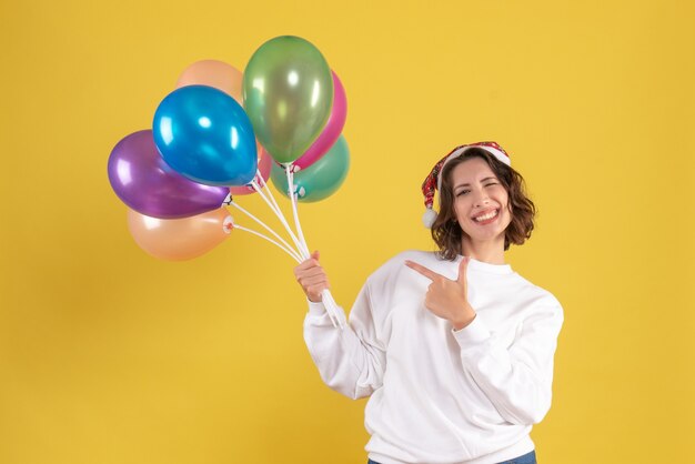 Vista frontal joven sosteniendo globos de colores en amarillo