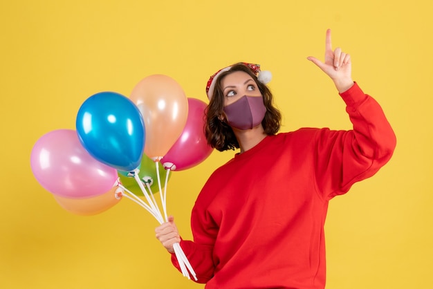 Vista frontal joven sosteniendo globos en máscara en amarillo