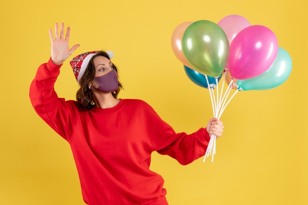 Vista frontal joven sosteniendo globos en máscara estéril en amarillo