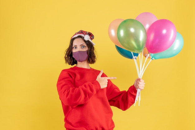 Foto gratuita vista frontal joven sosteniendo globos en máscara estéril en amarillo