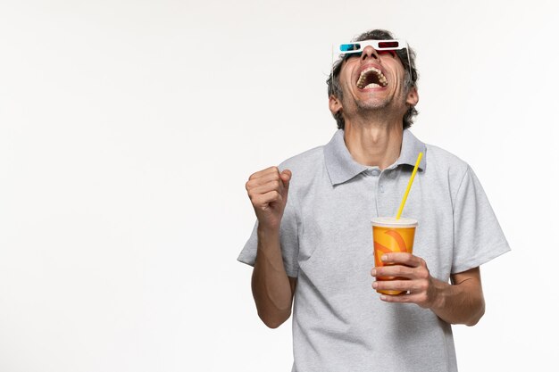 Vista frontal joven sosteniendo soda en d gafas de sol en la pared blanca películas remotas disfrute solitario