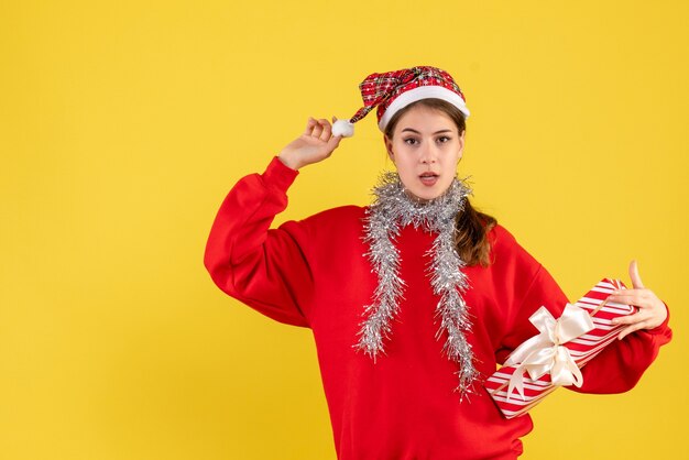 Vista frontal joven con suéter rojo con regalo y su gorro de santa