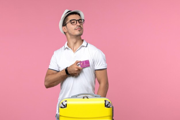 Vista frontal del joven con tarjeta bancaria en vacaciones de verano en la pared rosa