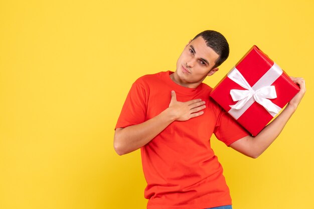 Vista frontal, de, joven, tenencia, navidad, presente, en, pared amarilla