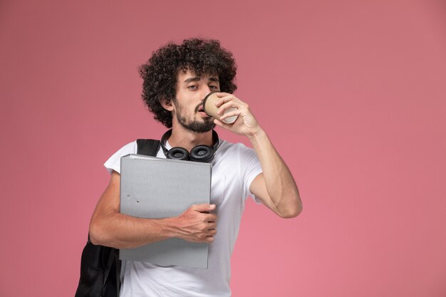 Vista frontal joven tomando café y sosteniendo la carpeta