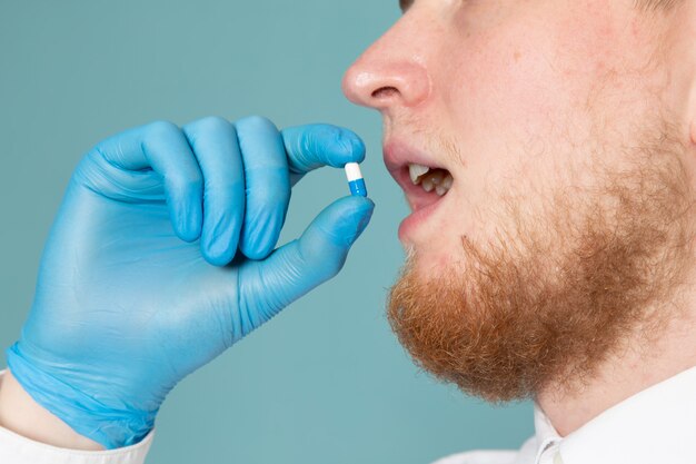 Una vista frontal joven tomando pastillas en guantes azules