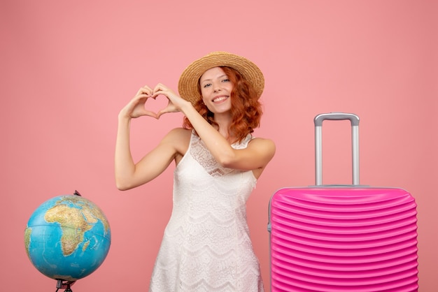 Vista frontal de la joven turista con bolsa rosa en la pared de color rosa claro