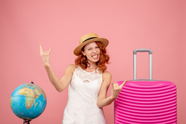 Vista frontal de la joven turista con bolsa rosa en pared rosa
