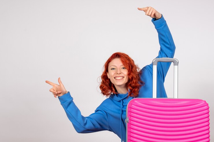 Vista frontal de la joven turista con bolsa rosa sobre pared blanca