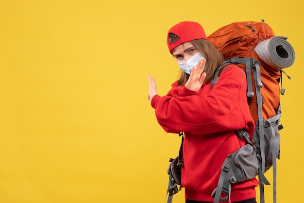 Vista frontal joven turista con mochila turística y máscara cruzando las manos