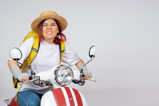 Vista frontal joven turista montando motocicleta en pared blanca mujer turista paseo velocidad del vehículo