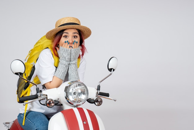 Vista frontal joven turista sentado en motocicleta en pared blanca velocidad mujer paseo en vehículo turístico