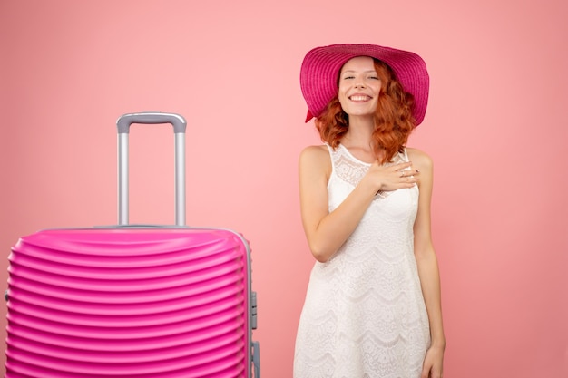 Vista frontal de la joven turista con sombrero rosa y bolso en pared rosa