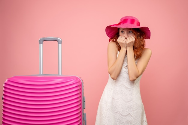 Vista frontal de la joven turista con sombrero rosa y bolso en pared rosa