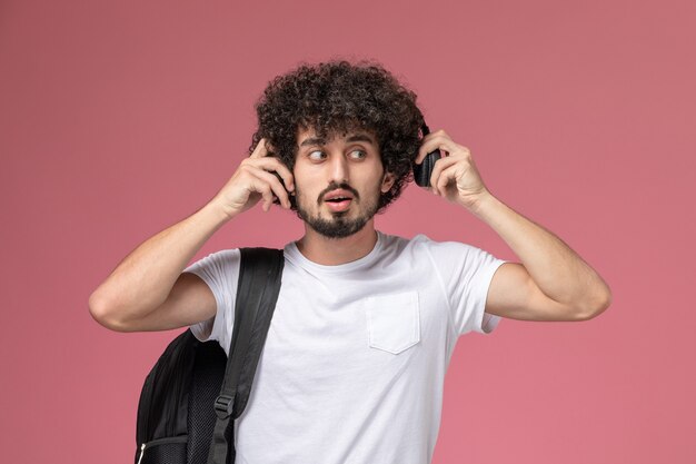 Vista frontal joven usando un lado de los auriculares para escuchar la canción