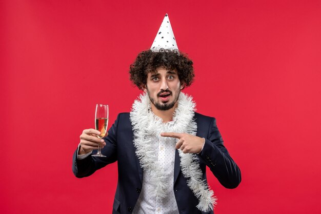 Vista frontal joven varón celebrando el año nuevo que viene en la pared roja fiesta navideña