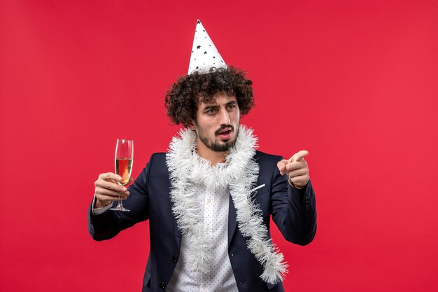 Vista frontal joven varón celebrando el año nuevo que viene en la pared roja fiesta navideña