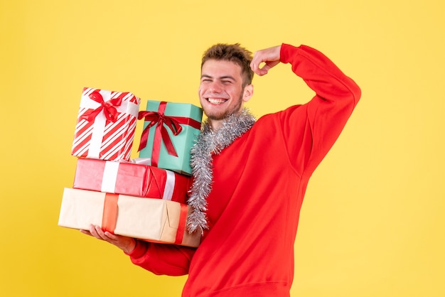 Vista frontal joven varón sosteniendo regalos de Navidad