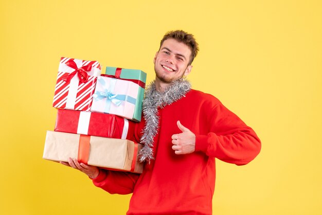 Vista frontal joven varón sosteniendo regalos de Navidad