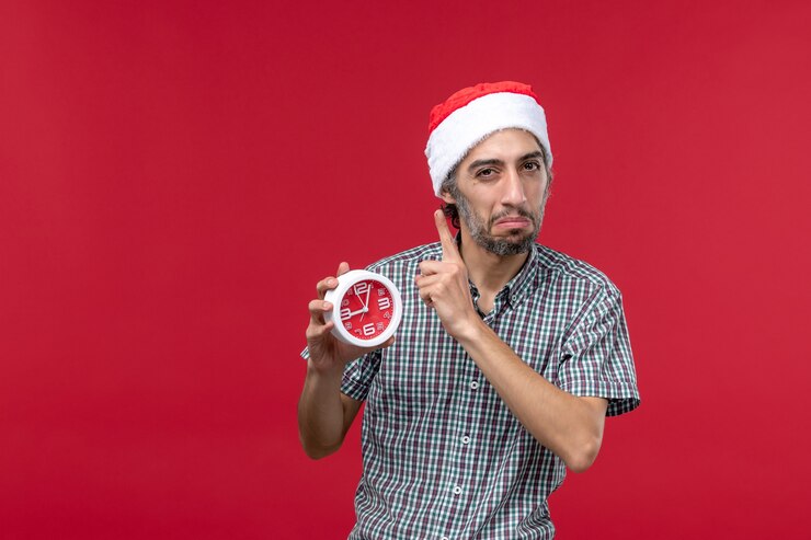 Foto gratuito vista frontal joven varón sosteniendo relojes redondos sobre el fondo rojo.
