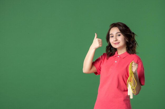 Vista frontal joven vendedora sosteniendo saltar la cuerda sobre fondo verde trabajador salud deporte boutique uniforme trabajo presente compra venta