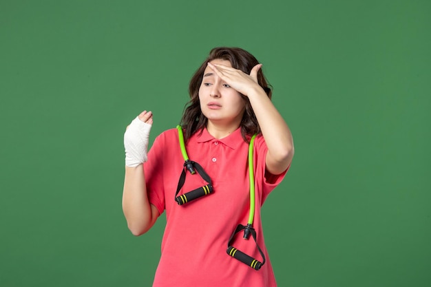 Vista frontal joven vendedora con vendaje en su mano herida sobre fondo verde trabajo color lesión compras trabajo uniforme hospital