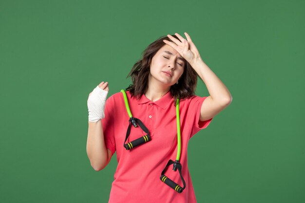 Vista frontal joven vendedora con vendaje en su mano herida sobre fondo verde trabajo color lesión salud trabajo uniforme hospital