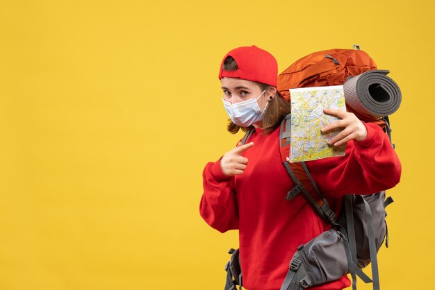 Vista frontal joven viajera con mochila y máscara con mapa