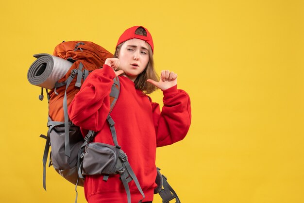 Vista frontal joven viajero con mochila apuntando a sí misma