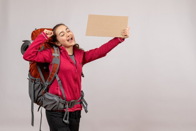Foto gratuita vista frontal joven viajero con mochila grande sosteniendo cartón
