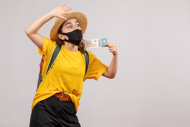 Vista frontal joven viajero con mochila sosteniendo boleto llamando a alguien