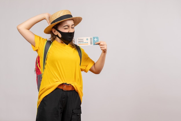 Vista frontal joven viajero con mochila sosteniendo boleto de viaje