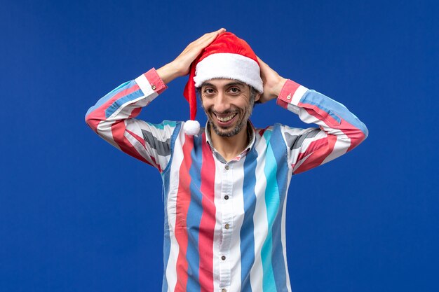 Vista frontal joven vistiendo gorra roja sonriendo, emoción masculina de navidad